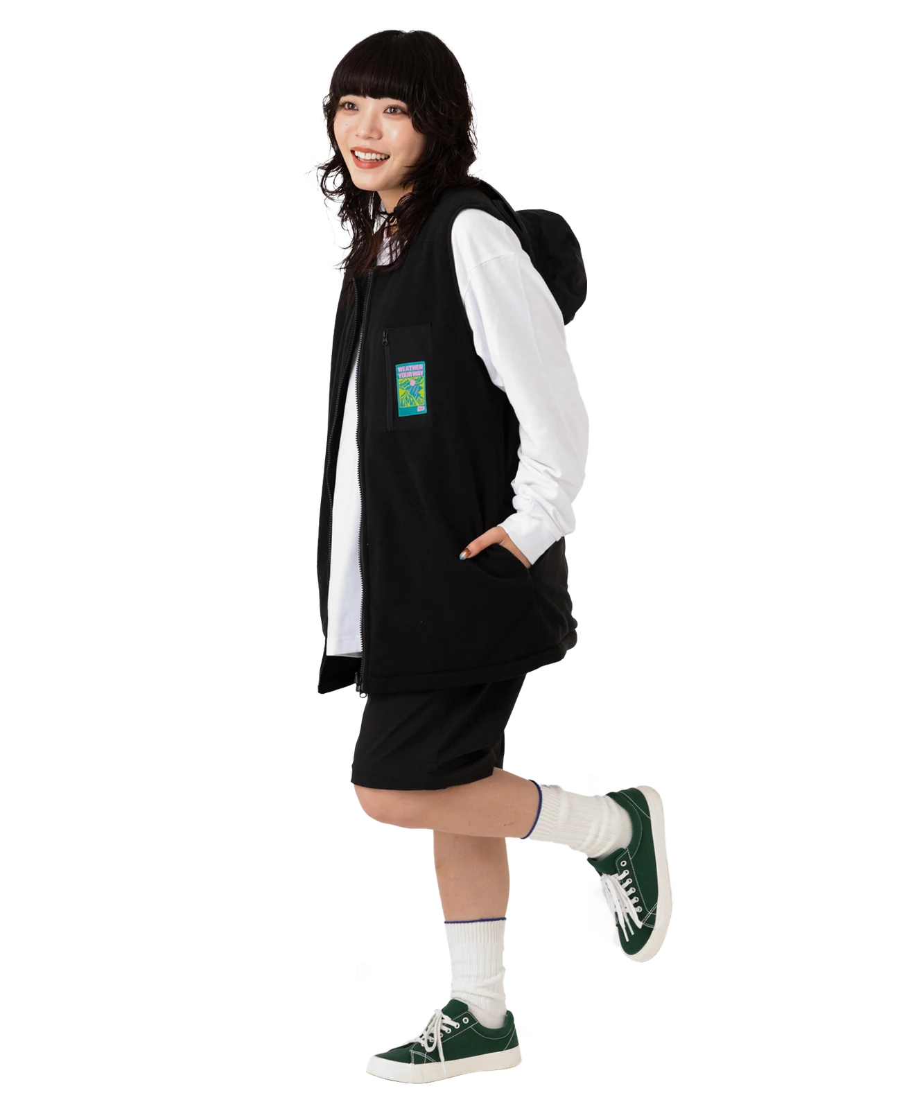 片足を上げたベストとショートパンツの全身コーデ